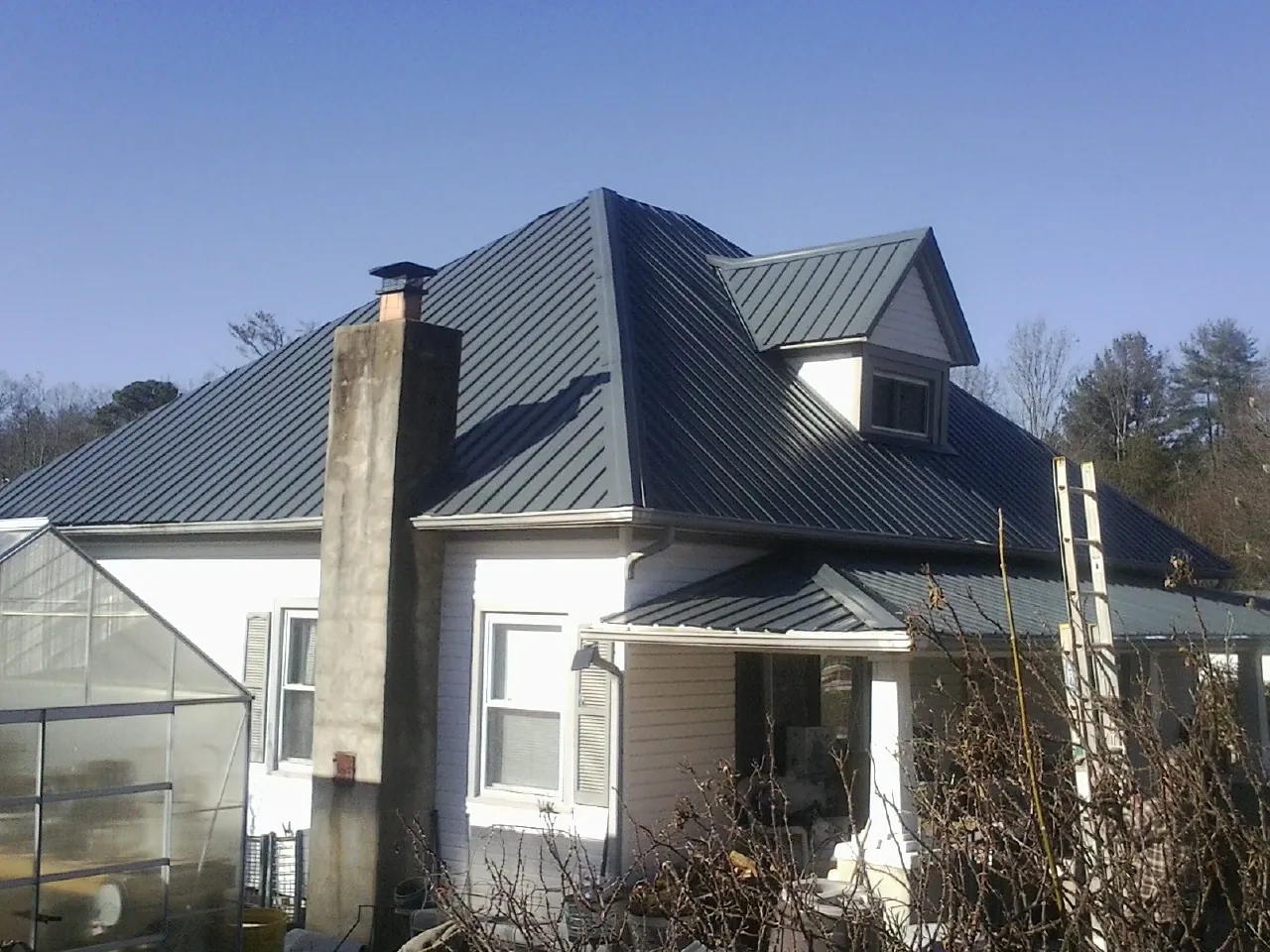 Dark blue standing seam metal roof on a white farmhouse with dormer — Slate & Tile Roof Repair by Roofing Brothers in Fitzwilliam