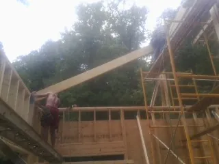 Carpenter raising a rafter beam on a new second story frame in Fitzwilliam