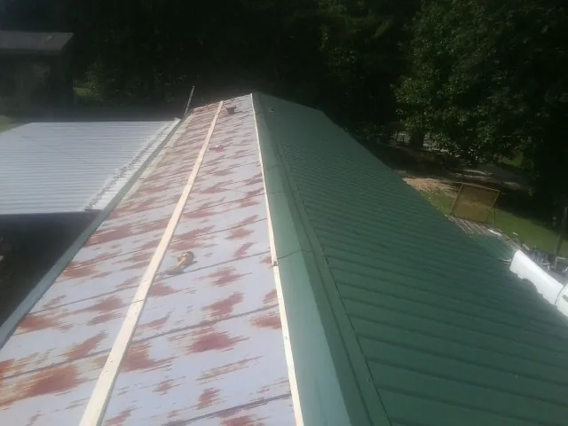 Old rusted panels beside newly installed green metal roofing — Wind Damage Roof Repair by Roofing Brothers in Fitzwilliam