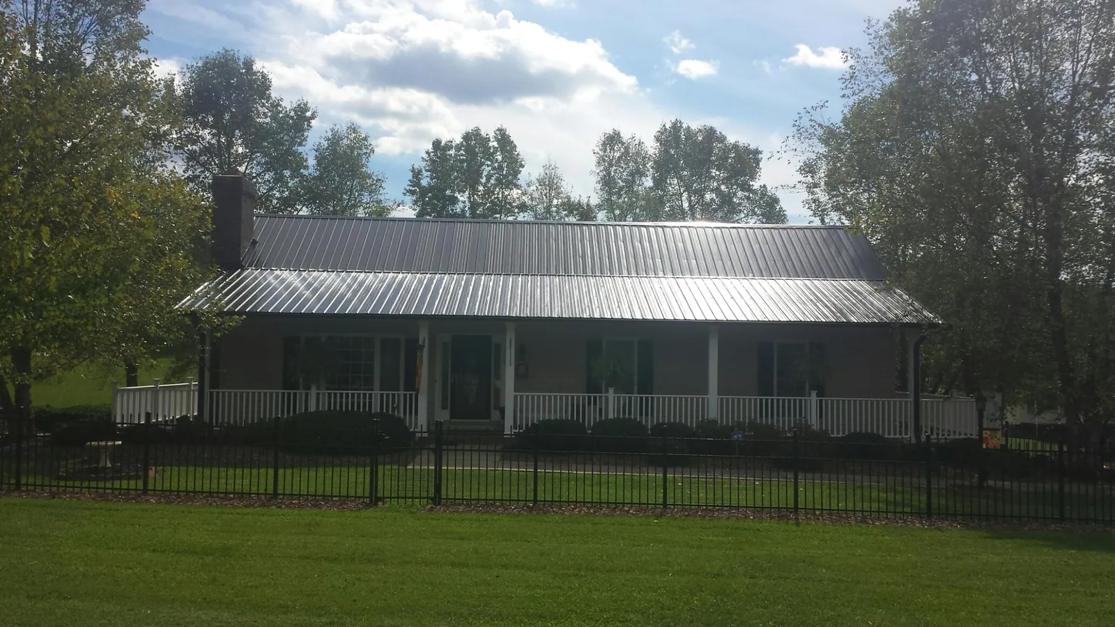 Gray metal roof on a brick ranch with a full width front porch — Gutter Guard Installation work by our crew in Fitzwilliam