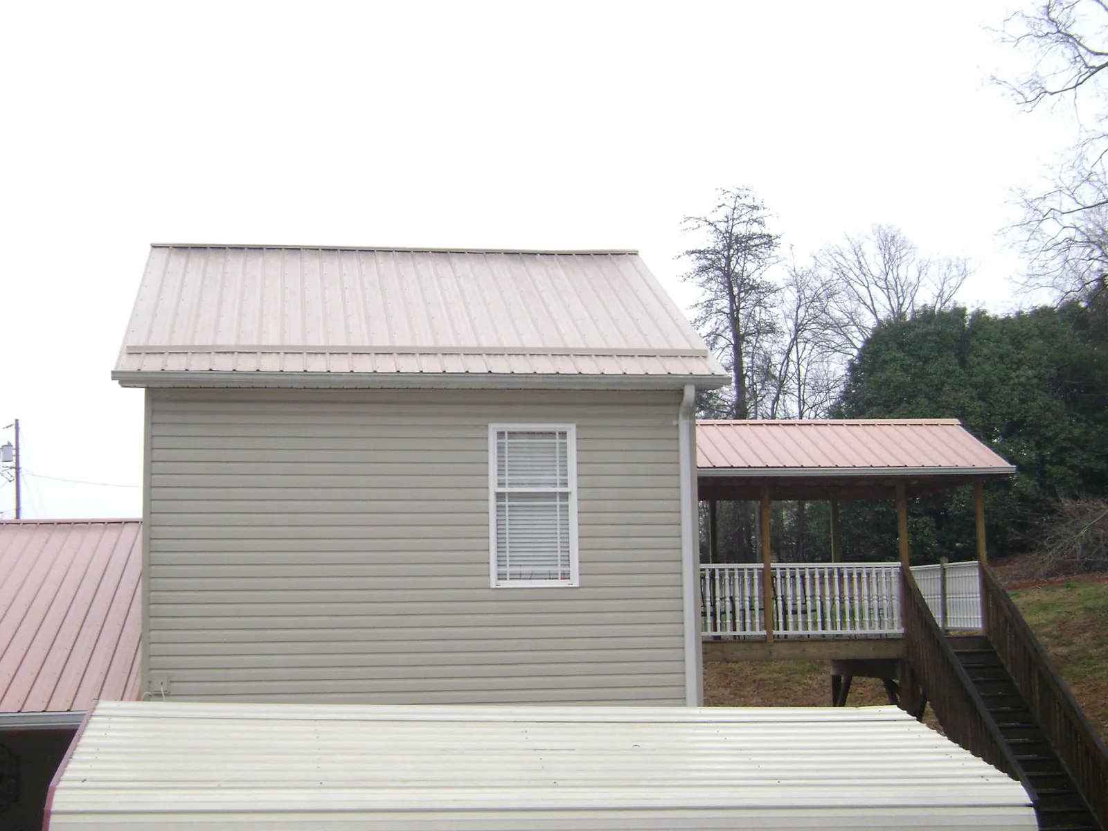Tan metal roofs on a two story addition and attached porch, from a Roof Replacement job in Fitzwilliam