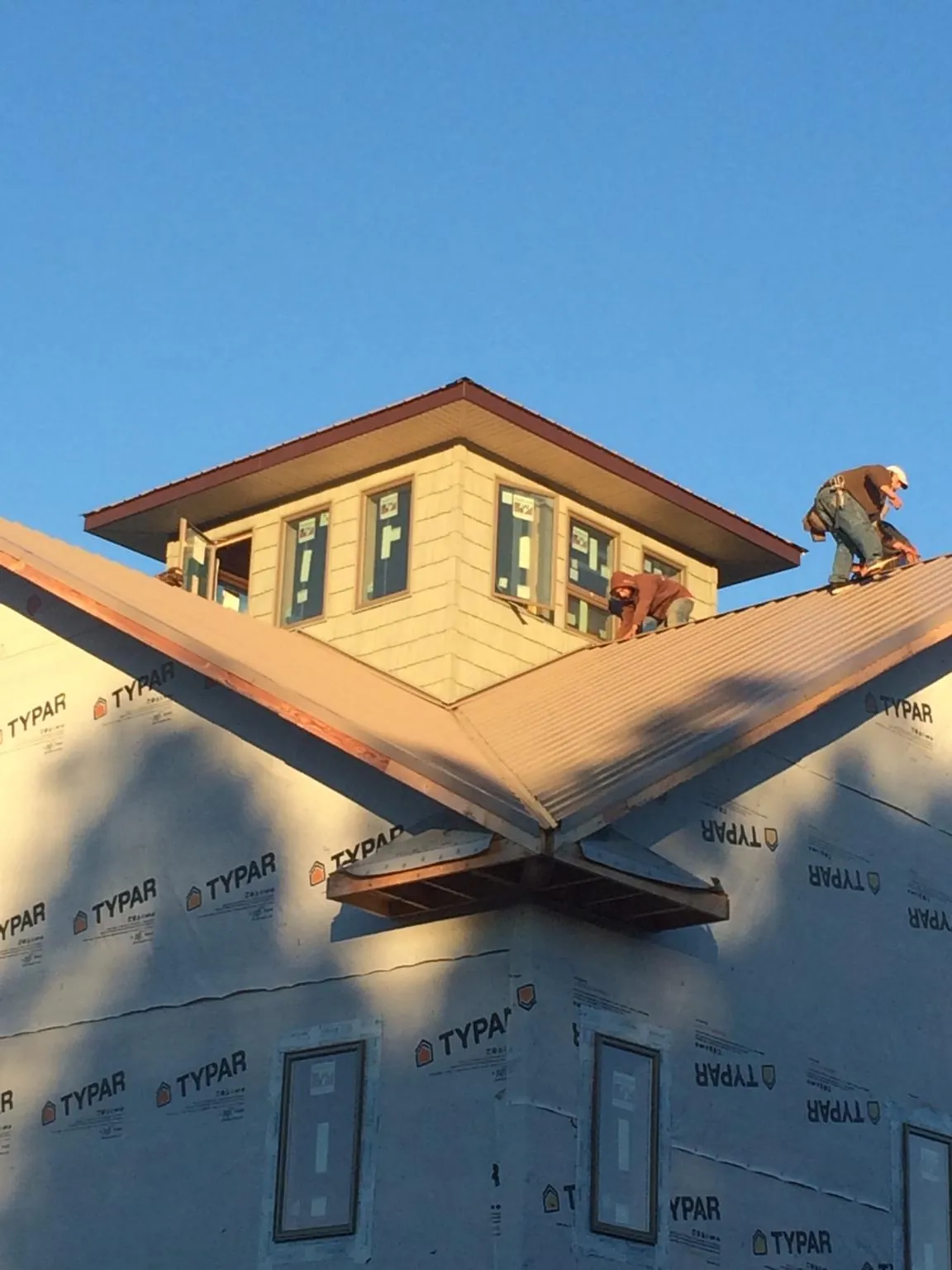 Roofers working around a rooftop cupola on a new metal roof at sunset — Roof Waterproofing in Fitzwilliam by Roofing Brothers